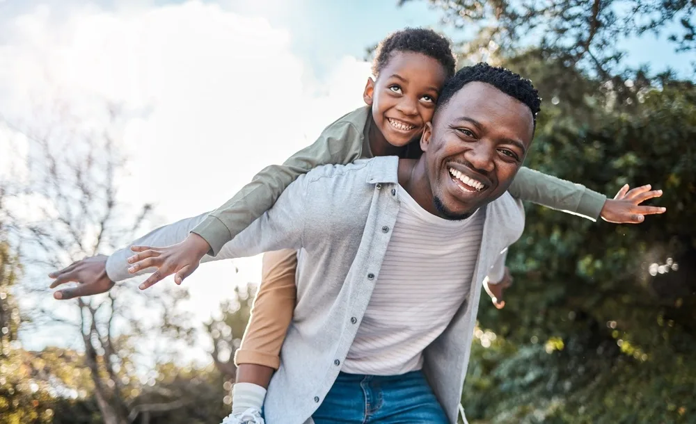 Root Canal Therapy Woodstock Father giving his child a piggyback ride outdoors